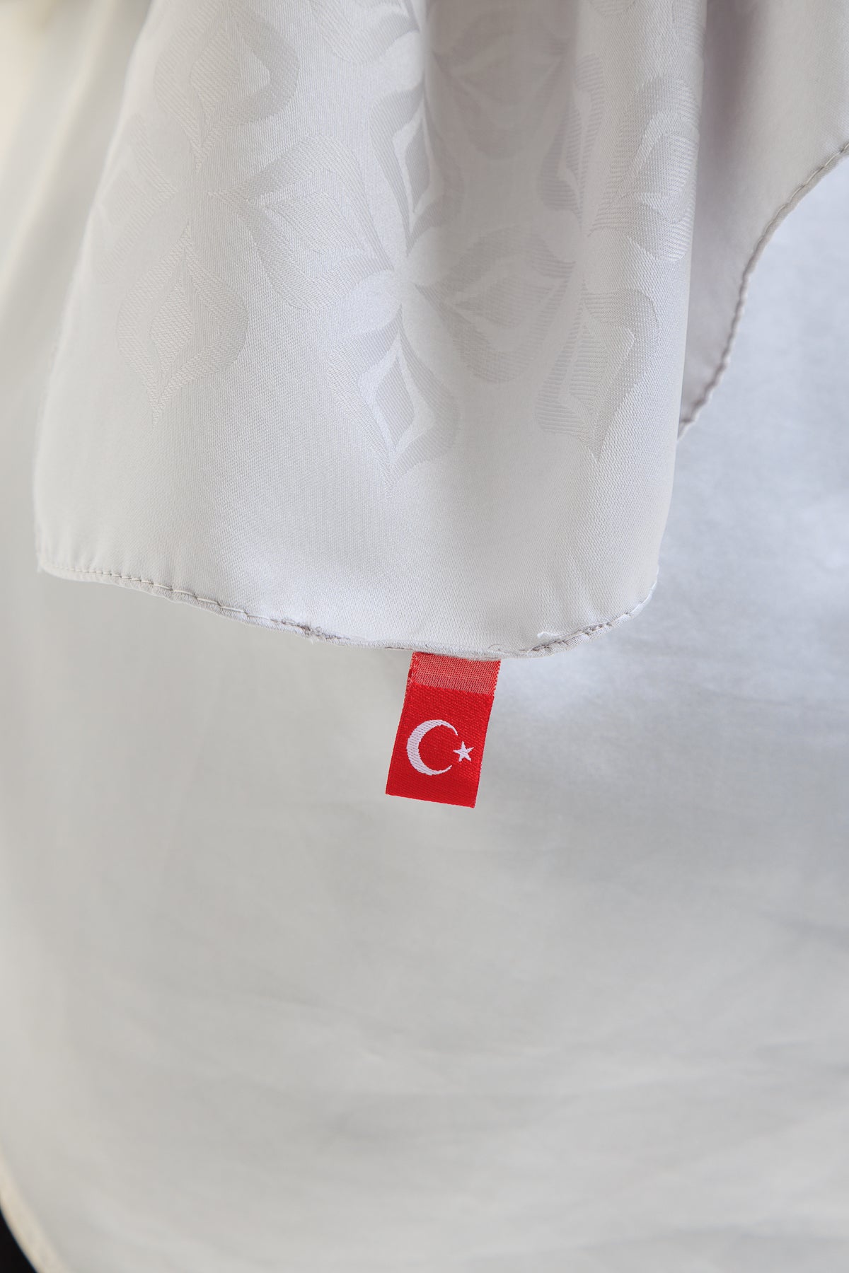 Close-up of a white hijab with a red label featuring a Turkish flag symbol.